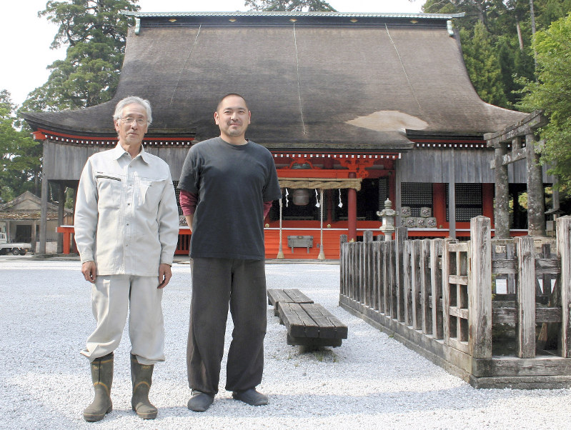 英彦山神宮の奉幣殿前に立つ高千穂秀敏宮司(左)と長男の有昭祢宜