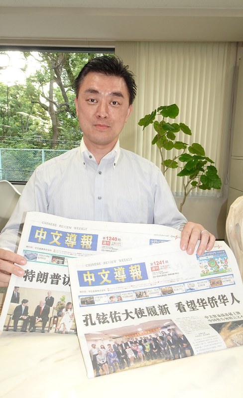 中国語紙「中文導報」の紙面を見せる編集長の楊文凱さん