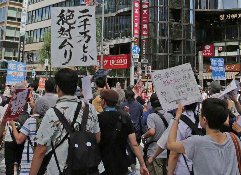 「二千万とか絶対ムリ」「年金払え!」などのプラカードを掲げて訴え行進するデモ参加者=東京・数寄屋橋交差点で2019年6月16日午後2時19分、山下浩一撮影