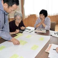 廃炉作業についての日ごろの疑問点を書いた付箋を模造紙に貼り、グループで考えをまとめる参加者たち＝福島県飯舘村草野の交流センターふれ愛館で