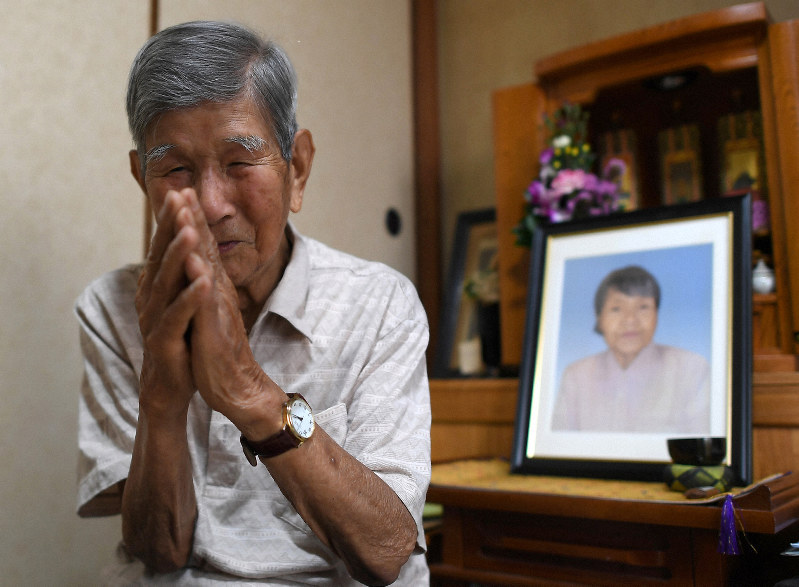 毎年、慰霊の日には沖縄の方角に向かって手を合わせるという吉村章さん。右奥は妻晴子さんの遺影=大阪市都島区で2019年6月19日、久保玲撮影