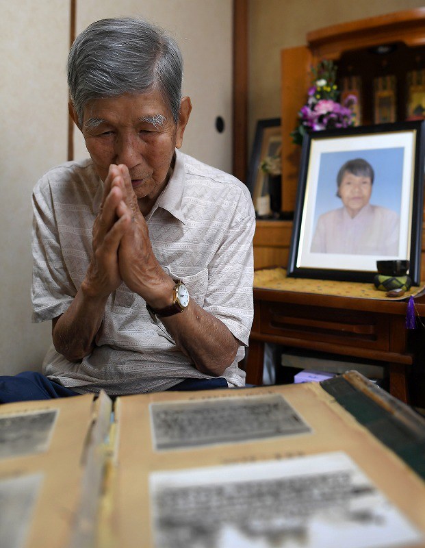 毎年、慰霊の日には沖縄の方角に向かって手を合わせるという吉村章さん。右奥は妻晴子さんの遺影=大阪市都島区で、久保玲撮影