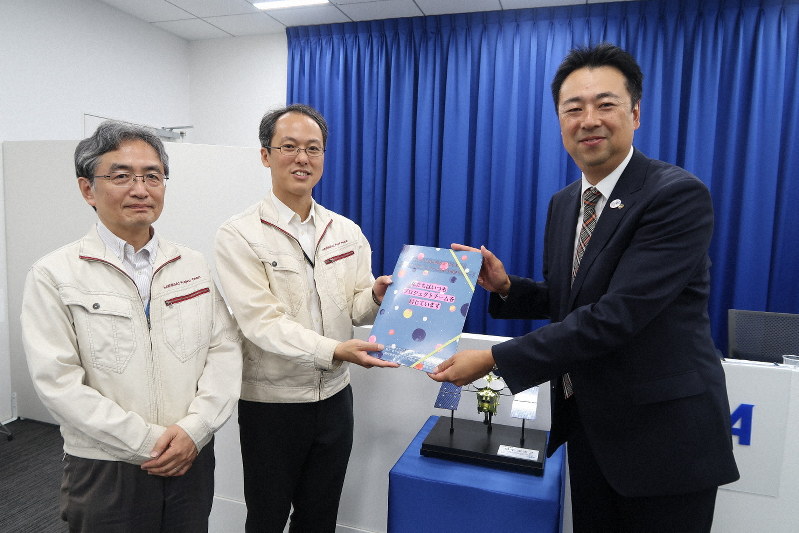 探査機はやぶさ2の2回目の着陸に向けて、津田雄一・プロジェクトマネジャー(中央)と吉川真・ミッションマネジャー(左)に応援メッセージを贈る梅岡久・大正製薬マーケティング本部長=東京都千代田区で2019年6月25日、永山悦子撮影
