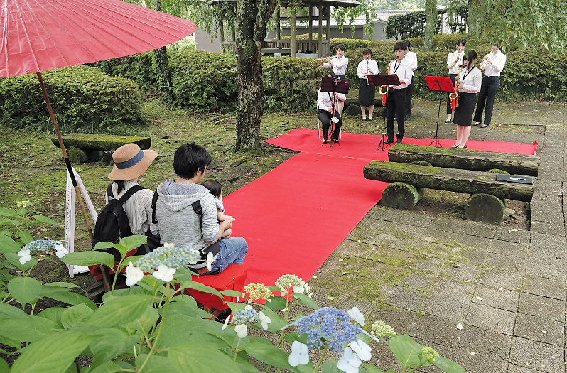 夫婦(左)に思い出に残る演奏をプレゼントする吹奏楽部員たち=栃木県大田原市の黒羽城址公園で