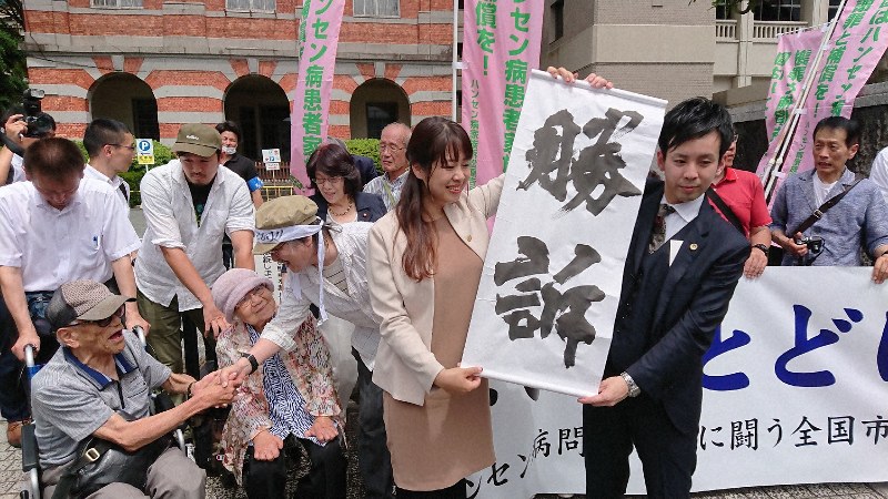 勝訴の紙を掲げる弁護士=熊本市の熊本地裁前で2019年6月28日、田鍋公也撮影