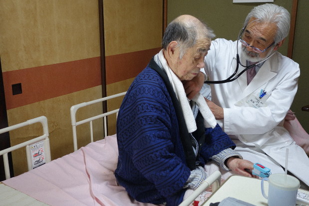訪問診療で80代男性の胸に聴診器を当てる高林さん