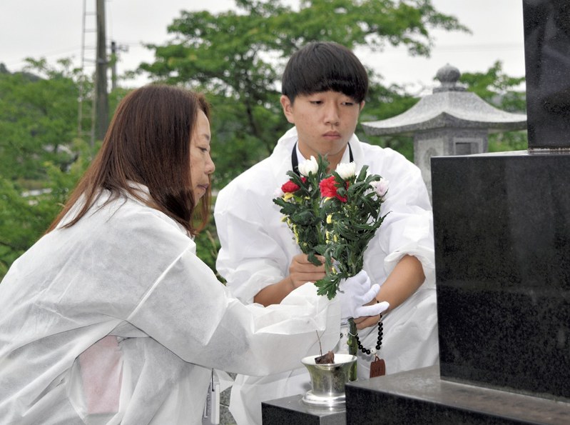 小畑大地さんは母明美さんと帰郷し、父一彦さんの遺骨を墓に納め花を供えた=福島県双葉町渋川で2019年6月29日午後1時20分、乾達撮影
