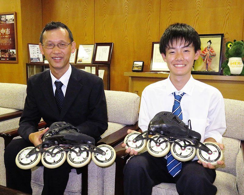インラインスピードスケートの靴を見せながら豊中かがやき大賞受賞を喜ぶ川口哲平さん(右)と小川真監督=大阪府豊中市役所で、三角真理撮影