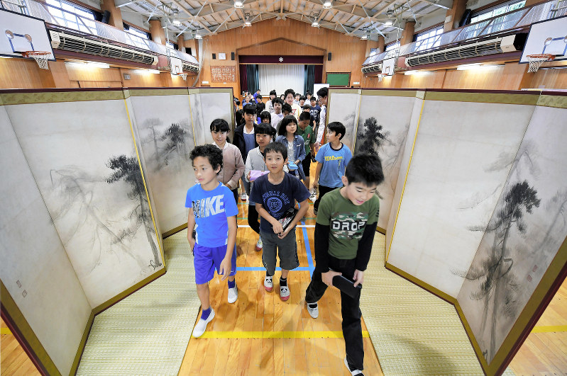 体育館で行われた出前授業で、向かい合わせに並べた国宝「松林図屏風」の高精細複製品を眺めながら通り抜ける児童たち=東京都板橋区の区立上板橋第二小で2019年6月15日、手塚耕一郎撮影