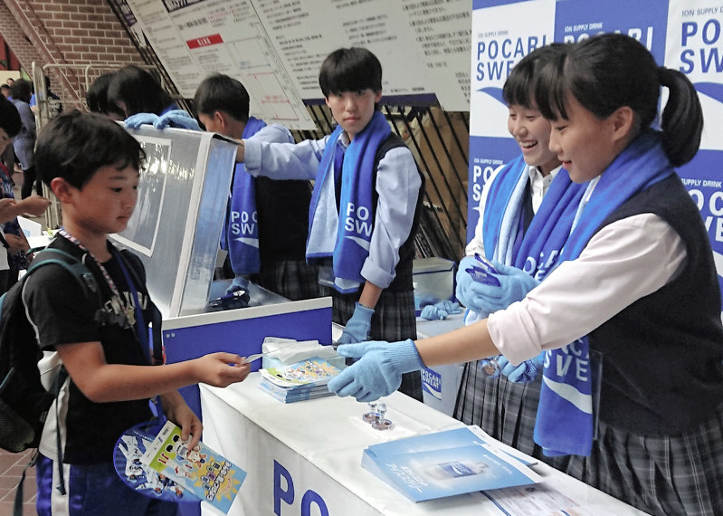 球場を訪れた子どもたちに熱中症予防の大切さを訴える高校生ボランティア=横浜市中区で