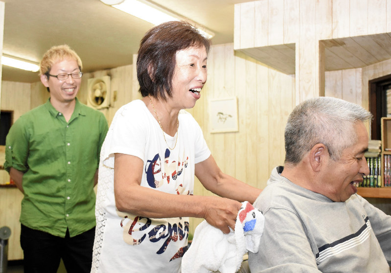 長男宙さん(左)の理髪店で働く兵頭千恵さん(中央)。なじみの客の散髪を終え、「また来てね」と笑顔を見せた=愛媛県西予市野村町地区で