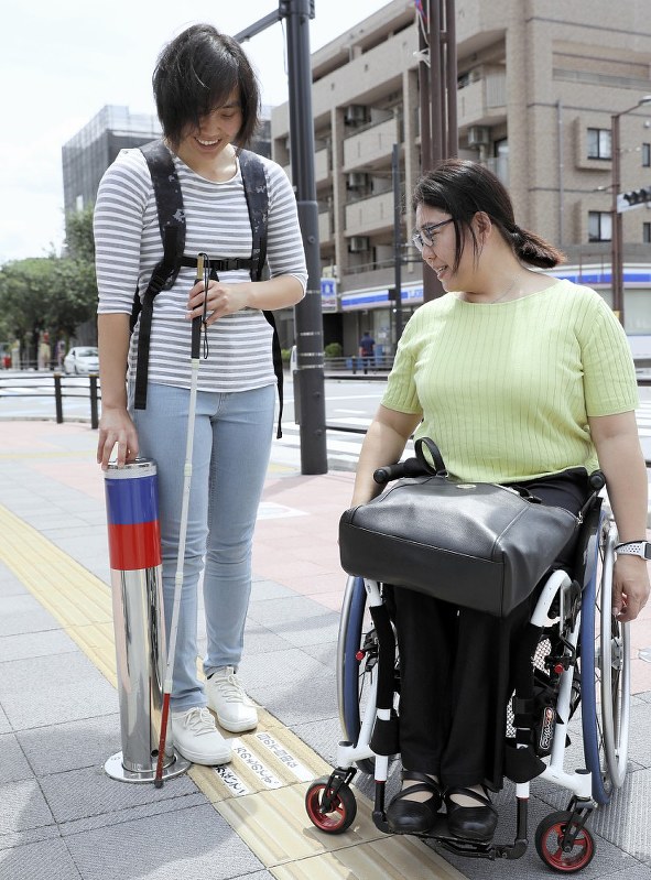 点字ブロックのそばに車止めのポールがあり、「歩行の際に危険ではないか」と指摘する大日方さん(右)と高田さん=東京都調布市で