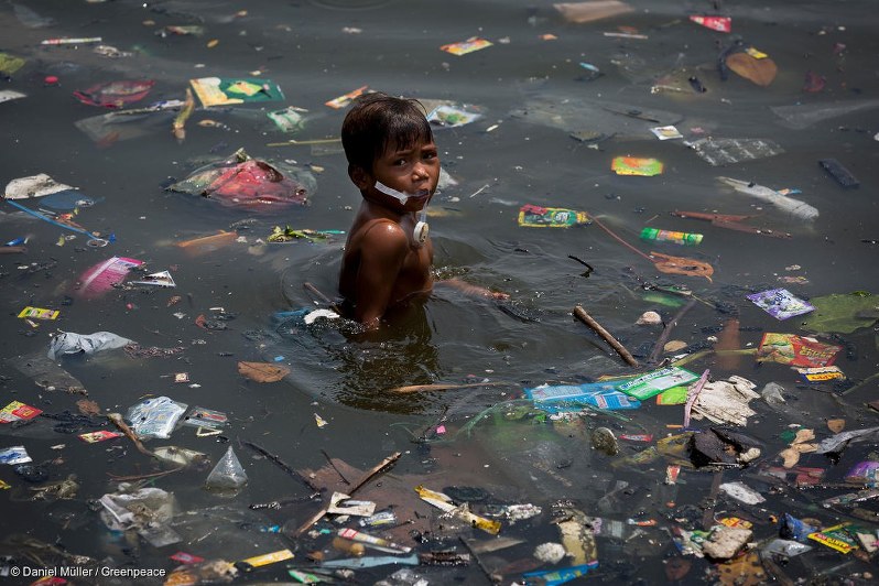 プラスチックごみが漂うフィリピン・マニラの海で泳ぐ子ども=国際環境NGO「グリーンピース」提供