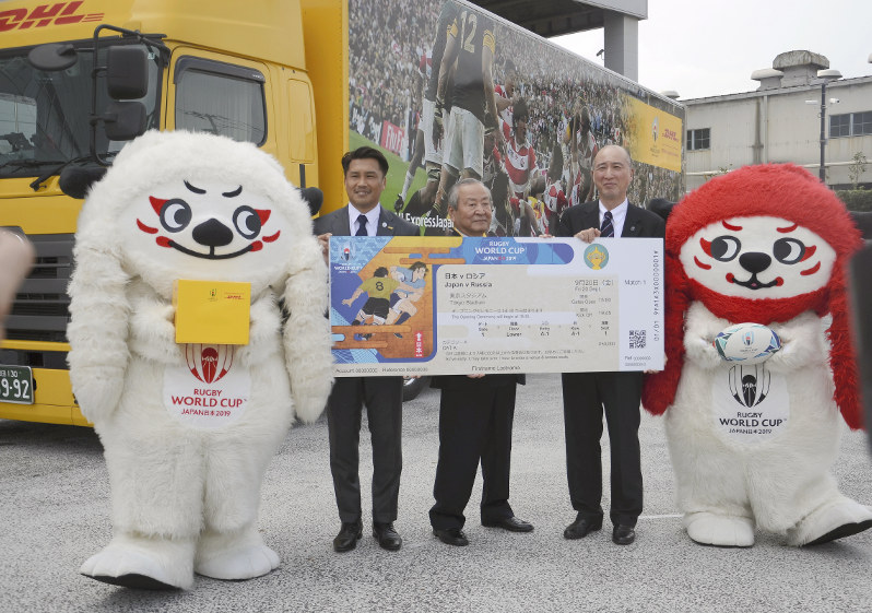 ラグビーW杯日本大会のチケットの発送が始まり、出発式に臨む(左から)公式マスコット「レン」、ラグビー元日本代表の大西将太郎さん、大会組織委の嶋津昭事務総長、DHLジャパンの山川丈人社長、「ジー」=東京都江東区で2019年7月18日、大谷津統一撮影