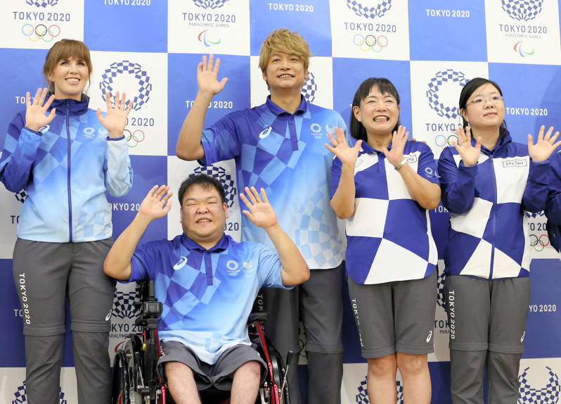 東京五輪・パラリンピックのボランティアらのユニホームが発表され、笑顔を見せる選考委員の香取慎吾さん(中央)。左がフィールドキャスト(大会ボランティア、スタッフ)用、右がシティキャスト(都市ボランティア)用=佐々木順一撮影