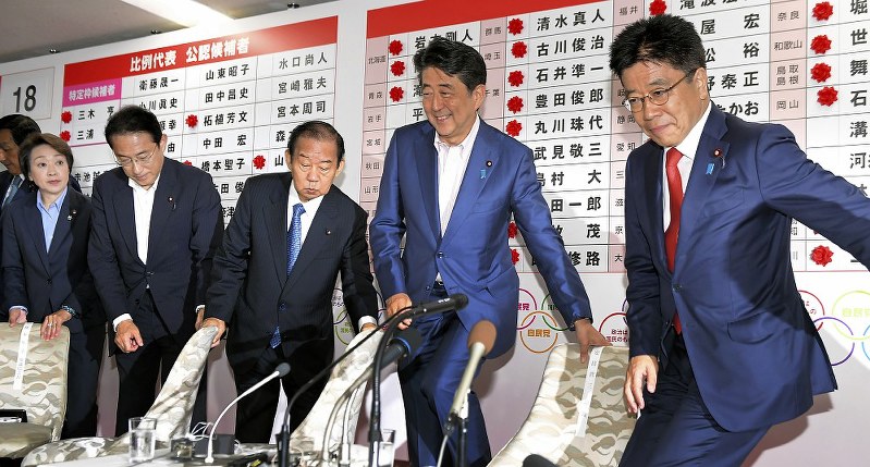 当選確実となった候補者の名前に花をつけた後、岸田文雄政調会長(右から4人目)ら自民党幹部と共に席に着く安倍晋三首相(同2人目)=東京都千代田区で2019年7月21日午後9時58分、滝川大貴撮影