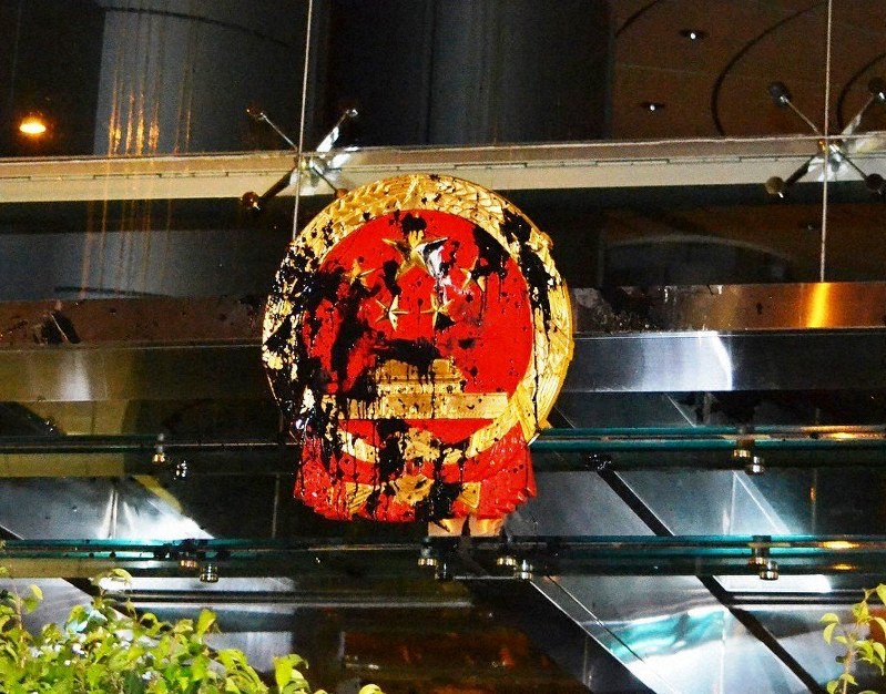 中国の出先機関「香港連絡弁公室」の正面玄関上部にある中国の国章は、黒い液体で汚されていた=香港で2019年7月21日午後8時18分、福岡静哉撮影