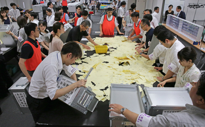 集まった投票箱から投票用紙を出し開票作業を行う千代田区の職員ら=東京都千代田区で2019年7月21日午後8時51分、山下浩一撮影