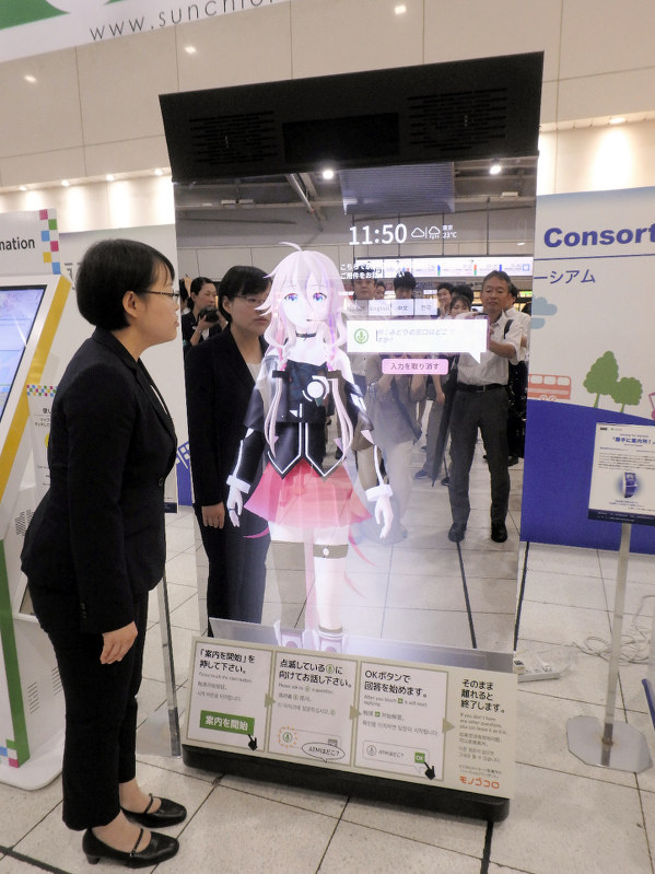 大画面を使ったAIデジタルサイネージに質問をする関係者=品川駅で