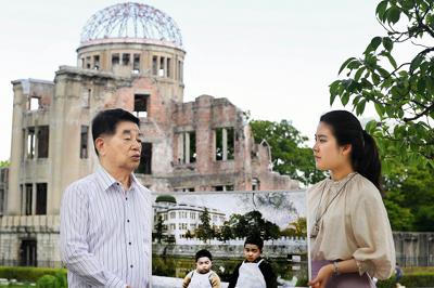 被爆死した兄玉三さんと一緒に写った写真のパネルを手にする旧中島地区住民の浜井徳三さん（85歳＝左、パネルの写真も）と、カラー化を手がけた庭田杏珠さん。後方は原爆ドーム（旧県産業奨励館）＝広島市中区で２０１９年６月１６日、山田尚弘撮影