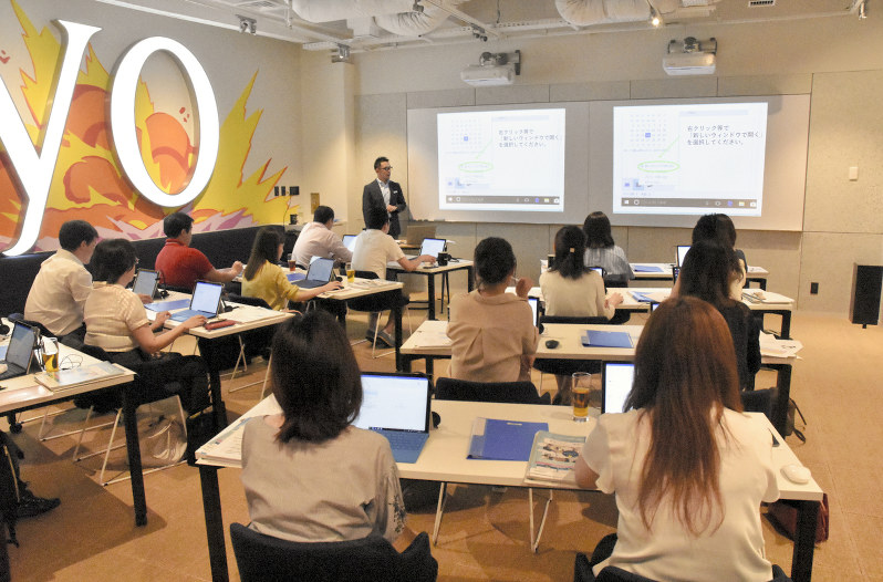 テレワークの体験セミナーで、講師(左奥)の話に耳を傾ける参加者ら=港区で