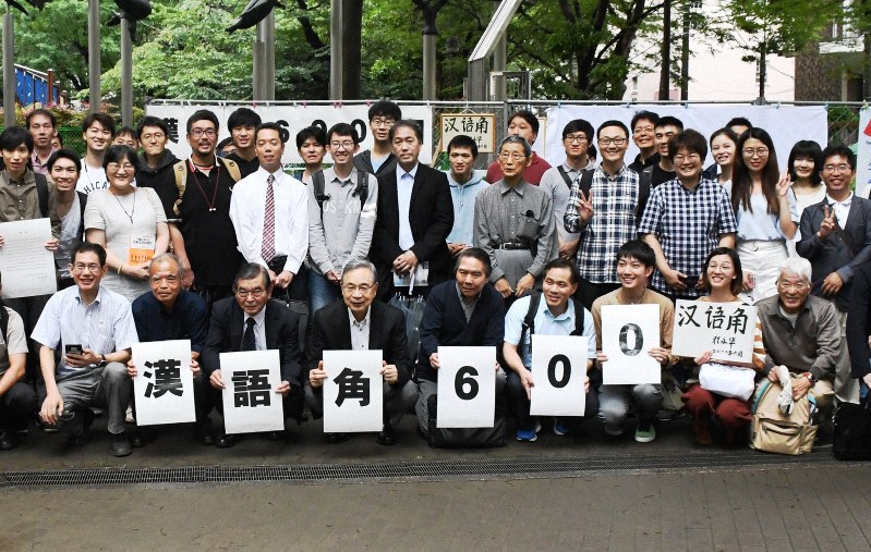 「日曜日の中国語コーナー」の開催600回を祝い、記念写真に納まる参加者たち。前列左端が主宰する段躍中さん、同左から4人目が宮本雄二・元駐中国大使=東京都豊島区の西池袋公園で2019年7月14日、鈴木玲子撮影
