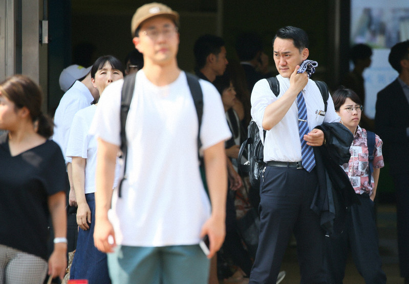 汗をぬぐいながら信号待ちをする男性(右奥)=東京都新宿区で2019年7月29日午後3時11分、吉田航太撮影