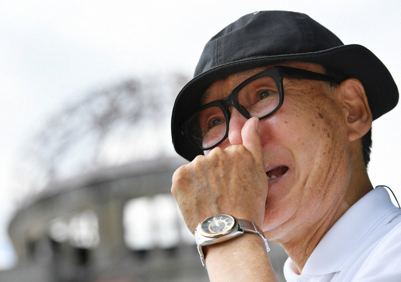 原爆ドームの前で言葉を詰まらせながら亡くなった母や姉について語る金本弘さん=広島市中区で2019年8月5日、山田尚弘撮影