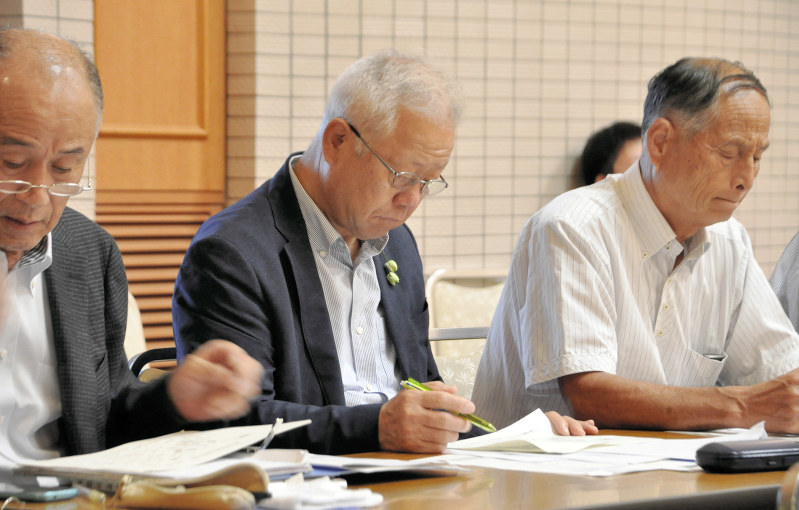 メモを取りながら原発事故被災地からの報告に耳を傾ける栃木県塩谷町の見形和久町長(中央)=福島市内のホテルで