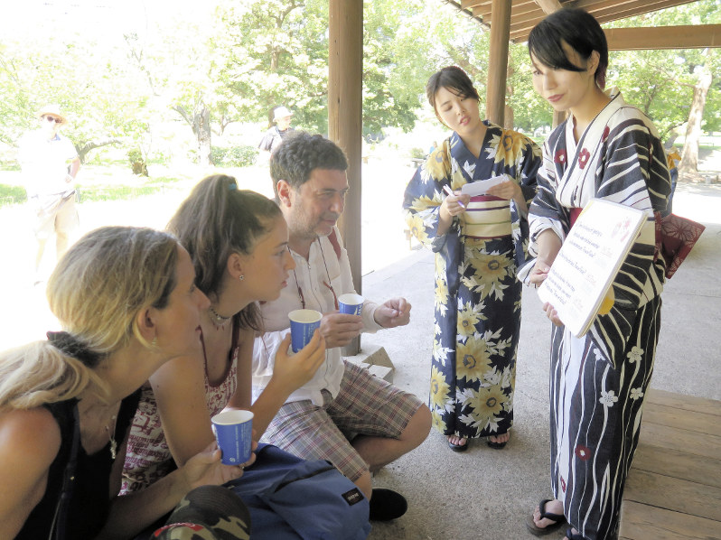 外国人観光客に熱中症について説明する学生=中央区の浜離宮恩賜庭園で