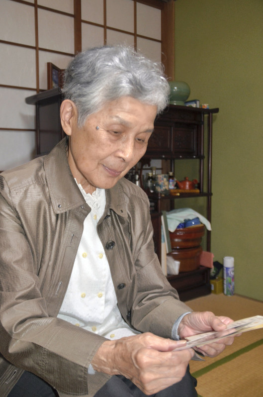 兄陽雄さんの勤務先周辺を撮影した写真を手に取る三浦さん=長崎市で2019年7月26日、田中韻撮影