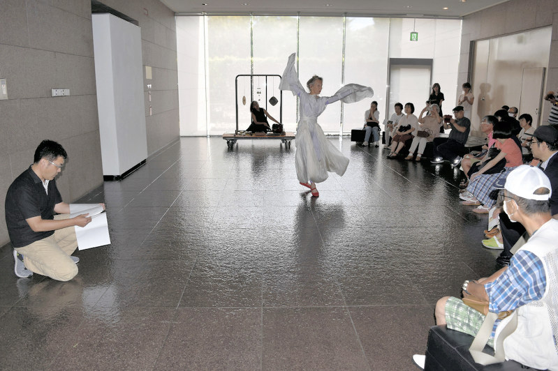 音と踊りのパフォーマンスと共に自作の詩を朗読する和合亮一さん(左)=福島県いわき市平の市立美術館で