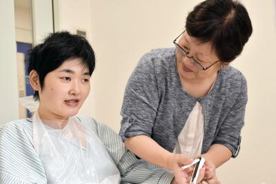 見舞い中、母（右）が爪を切ってあげながら語りかけると、娘の表情が少し和らいだ＝青森県で２０１９年８月１０日、岩崎歩撮影