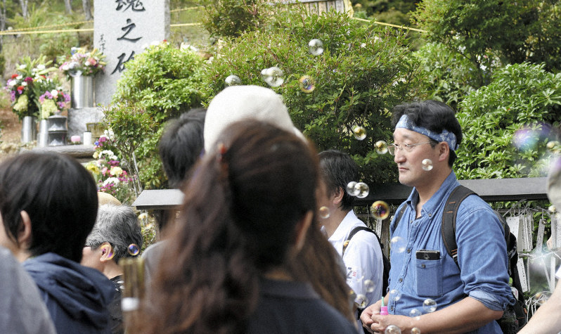 御巣鷹の尾根にある「昇魂之碑」の前で行われる慰霊式典でシャボン玉を吹き、亡き人について考える紫桃隆洋さん=2017年8月12日午前10時31分、神内亜実撮影
