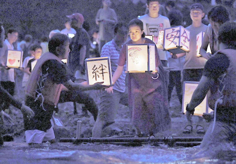 御巣鷹の尾根のふもとを流れる神流川に灯籠を流す人たち=群馬県上野村で午後7時2分、滝川大貴撮影
