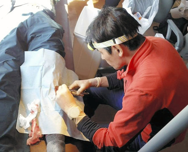 けがをした登山者の足の処置をする医師=西穂高診療所運営委員会提供