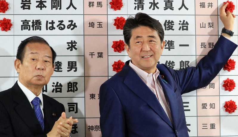 参院選の投開票日、自民党の二階俊博幹事長(左)と共に当選確実となった候補者の名前に花をつける安倍晋三首相=東京都千代田区で2019年7月21日午後9時56分、梅村直承撮影