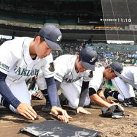 作新学院に敗れ、グラウンドの土を集める岡山学芸館の選手たち＝阪神甲子園球場で、森園道子撮影