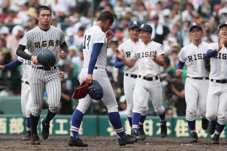 【履正社-明石商】決勝進出を決め喜ぶ履正社の選手たちと、残念そうな表情を見せる明石商先発の中森(左)=阪神甲子園球場で2019年8月20日、幾島健太郎撮影