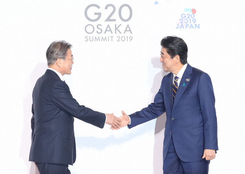 韓国の文在寅大統領(左)を出迎える安倍晋三首相=2019年6月28日、代表撮影