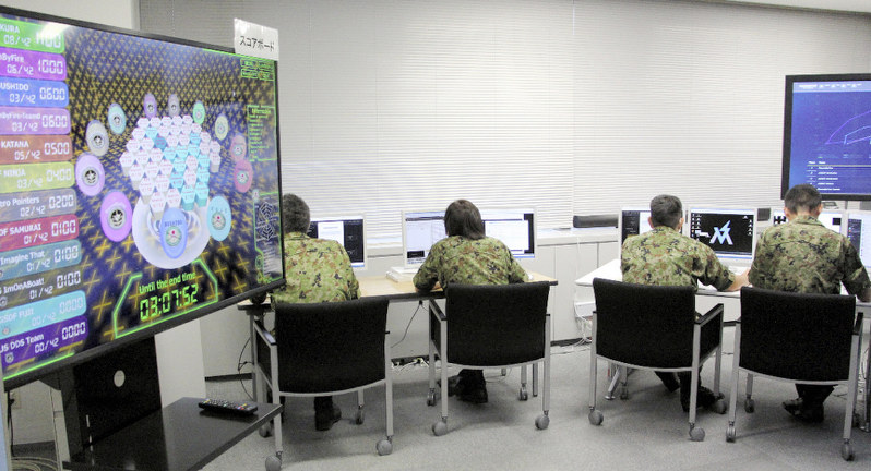 競技会に臨む陸上自衛隊システム防護隊の隊員。左にあるのは各チームの途中の得点が並んだスコアボード=東京都新宿区の防衛省で2019年8月22日午前5時52分