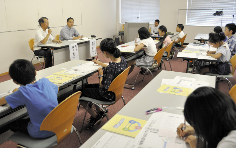 西川和之さん(奥の左側)から話を聞きながらメモを取る子どもたち=名古屋市東区で