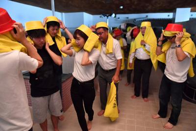 銭湯の浴室で地震が起きたと想定した訓練で、風呂桶をかぶって避難する参加者ら＝大阪市阿倍野区で２０１９年９月１日午前１０時４５分、小松雄介撮影