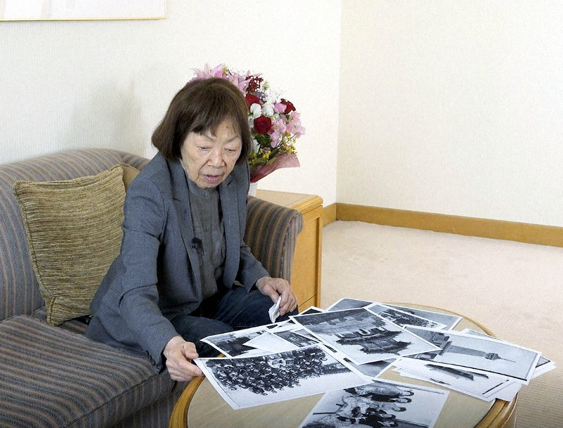 旧満州での写真を見ながらインタビューに応じる秋吉敏子さん=平和祈念展示資料館提供