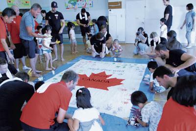 盛岡市内の保育園児たちと応援フラッグを作るカナダ水球男子の選手たち＝盛岡市のくりやがわ保育園で（盛岡市提供）