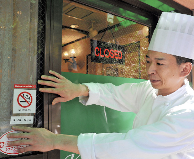 店頭に時間分煙を示すステッカーを貼った洋食店「レストラン桂」の店主=中央区日本橋室町1で影