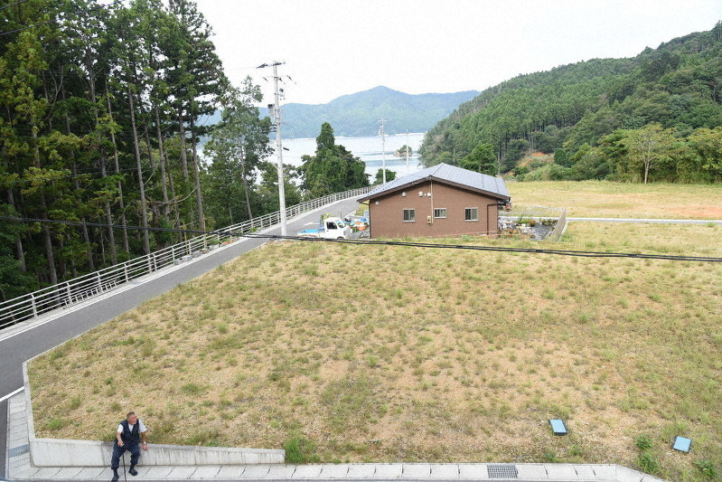 造成された地区にぽつんと建つ自宅(写真中央)から日課の散歩中、空き地で休憩をとる木村栄五郎さん=宮城県石巻市の分浜地区で2019年9月5日、百武信幸撮影
