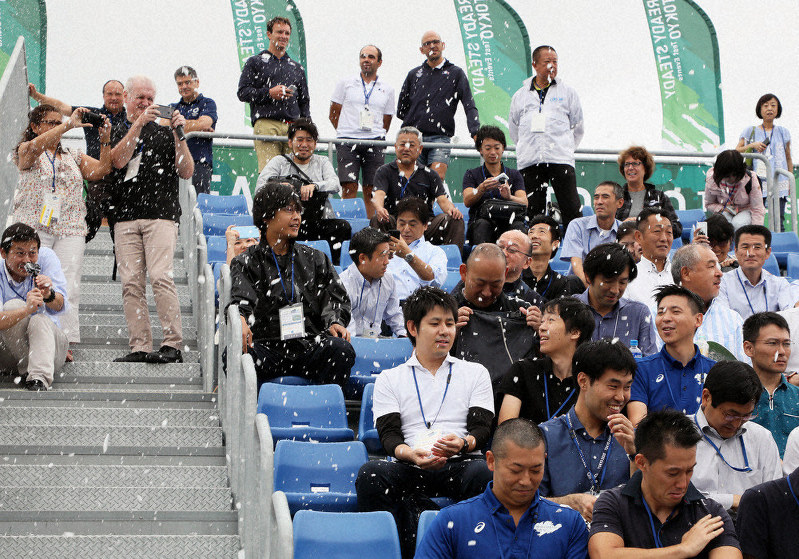 東京五輪・パラリンピックのカヌーのテスト大会で、観客席に降らせた暑さ対策の人工雪を浴びる人たち=東京都江東区で2019年9月13日、佐々木順一撮影
