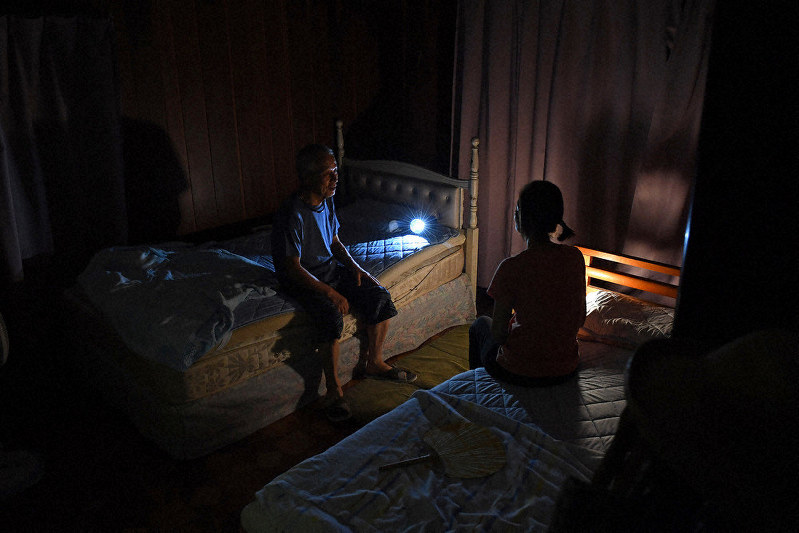 停電が続く自宅で懐中電灯をともして夜を過ごす夫婦。「片付けの疲れですぐ眠りに落ちても暑さで寝苦しい」と話した=千葉県館山市北条で2019年9月12日、北山夏帆撮影