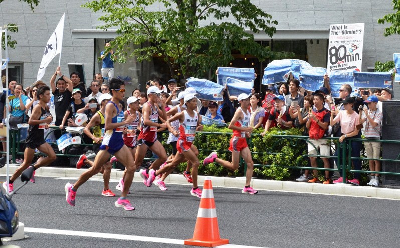 青く印刷されたMGC特集紙面で沿道を青く染めて応援する観戦者たち=東京都千代田区一ツ橋2で2019年9月15日午前10時38分、柳沢亮撮影